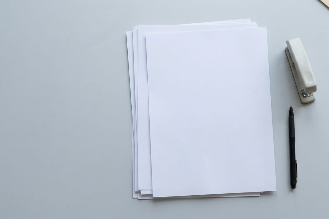 A short stack of blank sheets with a stapler and pen